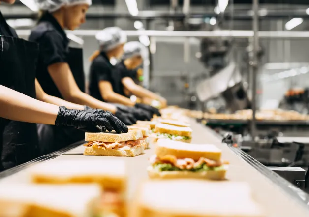 Gloved hands placing food by hand along a production line