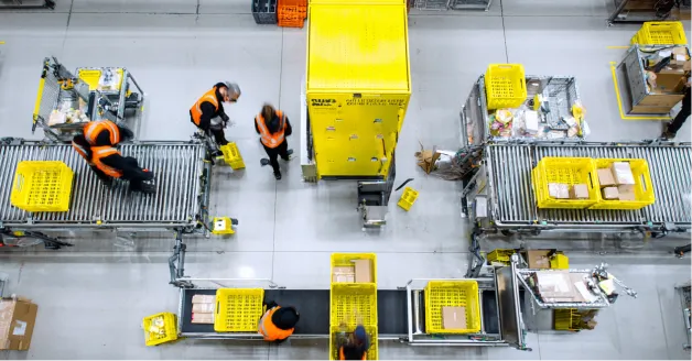 Workers sorting mixed goods by hand between warehouse conveyors